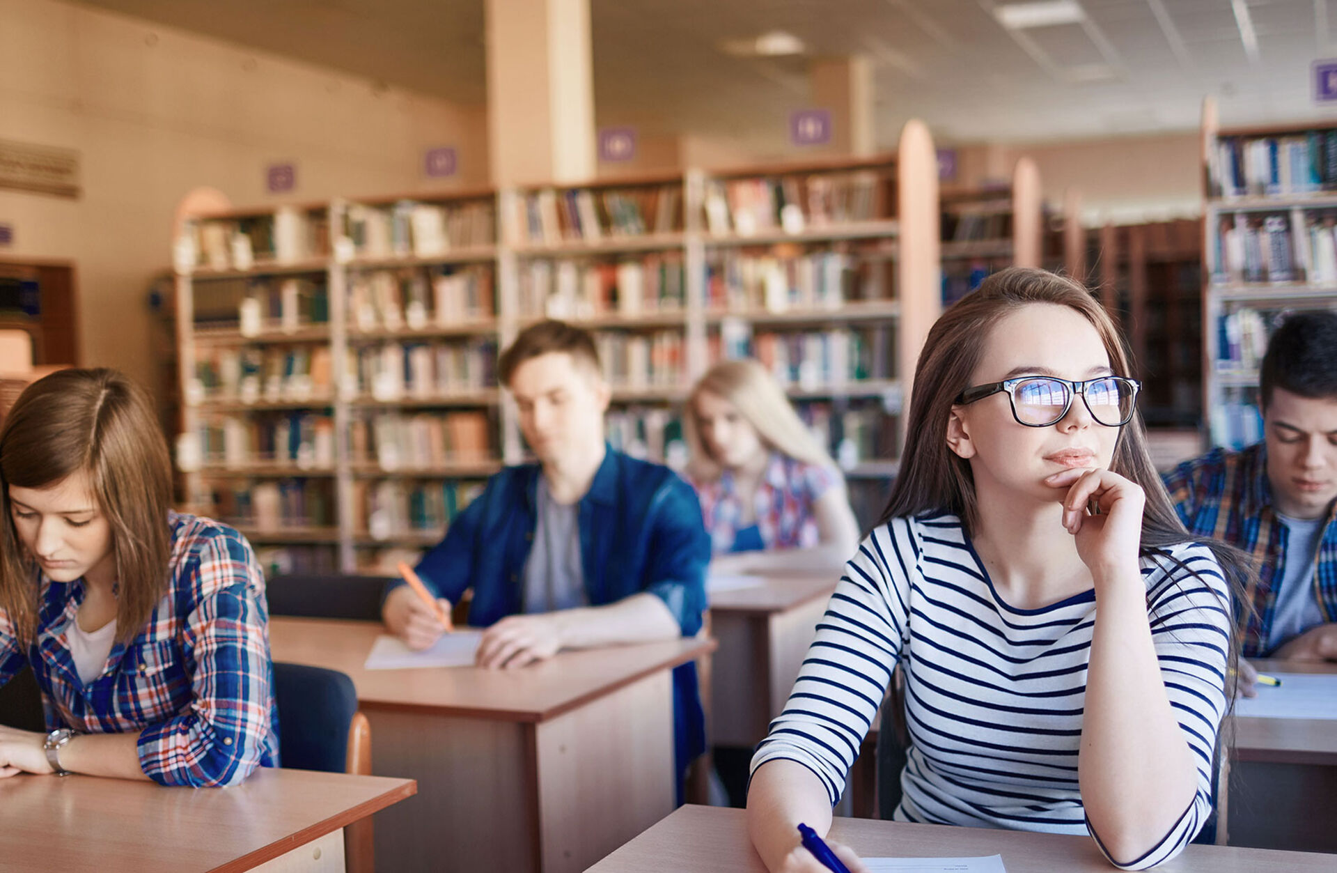 Studenten sitzen am Schreibtisch und folgen der Vorlesung
